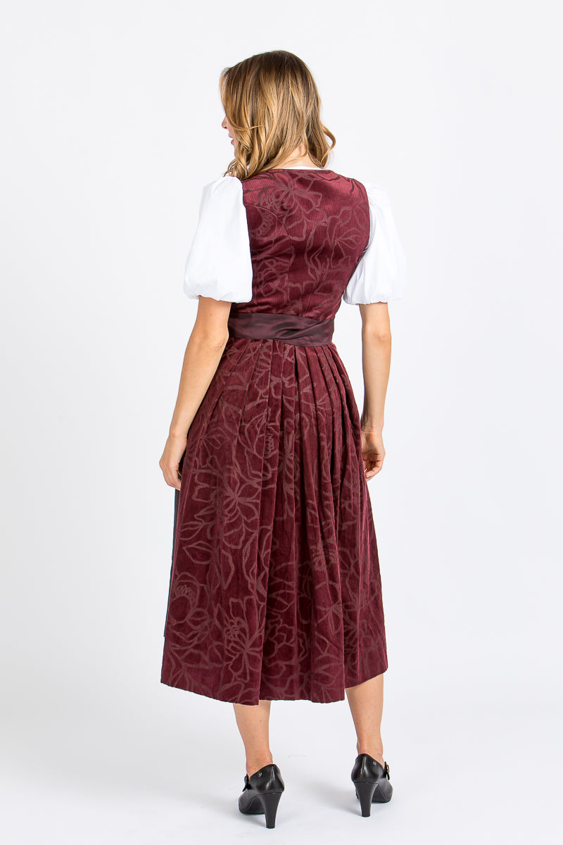 Almliebe Dirndl Loni in bordeaux in der Rückenansicht. HIer sieht man, dass das Dirndl durchgängig ist und man sieht das florale Muster.